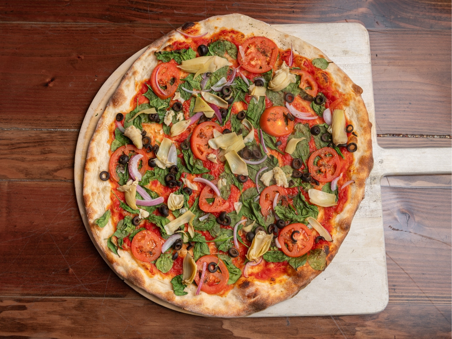 Vegan Pizza at Landinis Topped with Tomatoes Sauce,, Spinach, Fresh sliced Tomatoes, Red Onions, Artichokes, Black Olives.